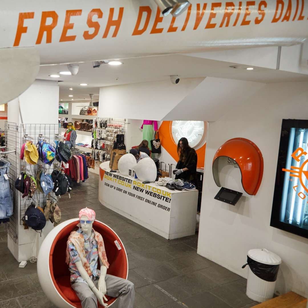 Geyim rəfləri və retro yumurta kreslosu olan vintaj mağazanın içi